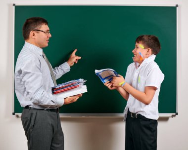 Düşük disiplinli bir öğretmen ve komik bir öğrencinin portresi. Öğrenci çok duygusal, eğlenceli ve çok mutlu, kara tahta arka planda poz - geri okul ve eğitim kavramı