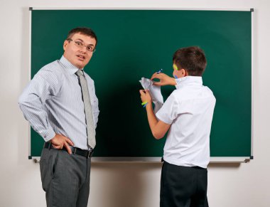 Düşük disiplinli bir öğretmen ve komik bir öğrencinin portresi. Öğrenci çok duygusal, eğlenceli ve çok mutlu, kara tahta arka planda poz - geri okul ve eğitim kavramı