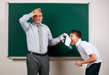 Düşük disiplinli bir öğretmen ve komik bir öğrencinin portresi. Öğrenci çok duygusal, eğlenceli ve çok mutlu, kara tahta arka planda poz - geri okul ve eğitim kavramı