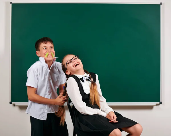 Portrait d'un écolier et d'une écolière jouant près du tableau noir - concept de retour à l'école et d'éducation — Photo