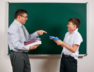 Düşük disiplinli bir öğretmen ve komik bir öğrencinin portresi. Öğrenci çok duygusal, eğlenceli ve çok mutlu, kara tahta arka planda poz - geri okul ve eğitim kavramı
