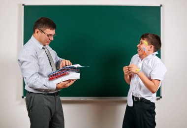 Düşük disiplinli bir öğretmen ve komik bir öğrencinin portresi. Öğrenci çok duygusal, eğlenceli ve çok mutlu, kara tahta arka planda poz - geri okul ve eğitim kavramı