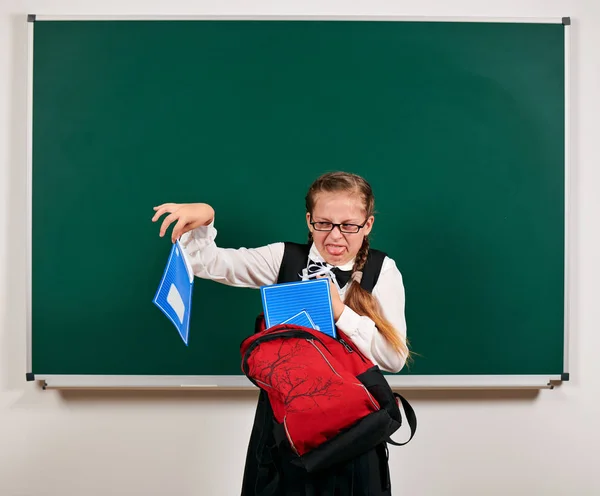 Portret van een schoolmeisje spelen met rugzak en schoolbenodigdheden in de buurt van Blackboard achtergrond-terug naar school en onderwijsconcept — Stockfoto