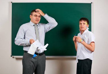Düşük disiplinli bir öğretmen ve komik bir öğrencinin portresi. Öğrenci çok duygusal, eğlenceli ve çok mutlu, kara tahta arka planda poz - geri okul ve eğitim kavramı