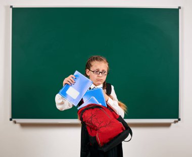 Sırt çantası ve kara tahta arka plan yakın okul malzemeleri ile bir kız öğrenci portresi - geri okul ve eğitim kavramı