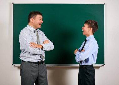 Bir adam ve çocuk kara tahta arka plan yakınında bir iş elbisesi giymiş portresi, onlar eğlenmek - öğrenme ve eğitim kavramı