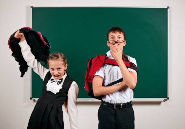 Bir okul çocuğu ve kız öğrenci nin kara tahta arka plan yakınında oynayan portresi - geri okul ve eğitim kavramı