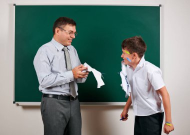Düşük disiplinli bir öğretmen ve komik bir öğrencinin portresi. Öğrenci çok duygusal, eğlenceli ve çok mutlu, kara tahta arka planda poz - geri okul ve eğitim kavramı