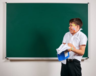 Komik öğrenci portresi. Okul çocuk çok duygusal, eğlenceli ve çok mutlu, kara tahta arka plan sahip - geri okul ve eğitim kavramı