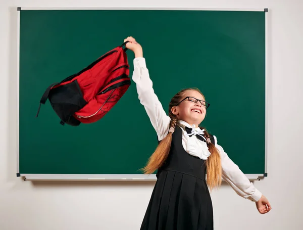 Portrait d'une écolière jouant avec un sac à dos et des fournitures scolaires près du tableau noir - concept de retour à l'école et d'éducation — Photo