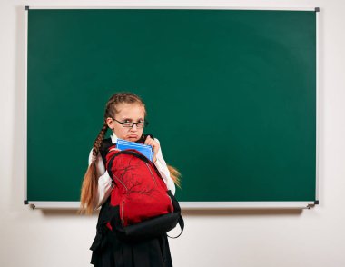 Sırt çantası ve kara tahta arka plan yakın okul malzemeleri ile bir kız öğrenci portresi - geri okul ve eğitim kavramı