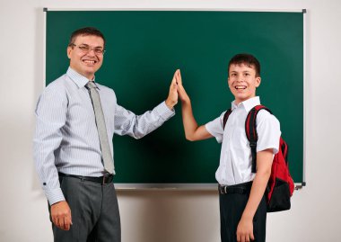 Bir öğretmen ve okul çocuğu kara tahta arka planda oynayan portresi - geri okul ve eğitim kavramı