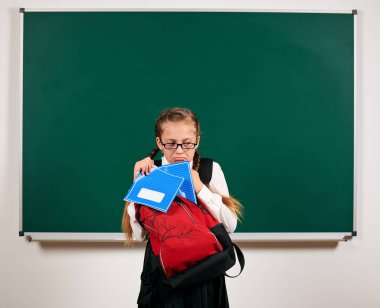 Sırt çantası ve kara tahta arka plan yakın okul malzemeleri ile bir kız öğrenci portresi - geri okul ve eğitim kavramı