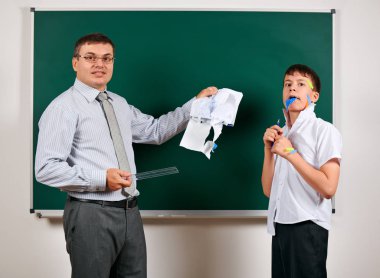 Düşük disiplinli bir öğretmen ve komik bir öğrencinin portresi. Öğrenci çok duygusal, eğlenceli ve çok mutlu, kara tahta arka planda poz - geri okul ve eğitim kavramı