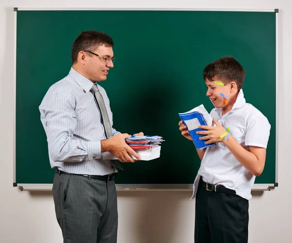 Portrait of a teacher and funny schoolboy with low discipline. Pupil very emotional, having fun and very happy, posing at blackboard background - back to school and education concept — Stock Photo, Image