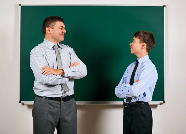 Portrait of a man and boy dressed in a business suits near blackboard background - learning and education concept — Stock Photo, Image