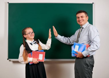 Bir öğretmen ve kız öğrenci portresi, kara tahta arka planda poz - geri okul ve eğitim kavramı