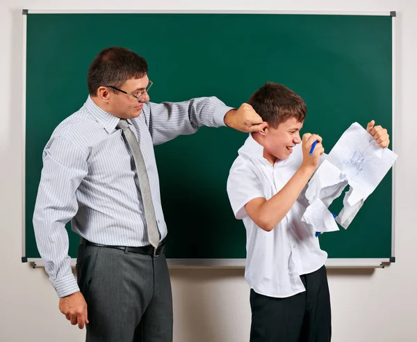 Portret van een leraar vangen het oor grappige school jongen met lage discipline. Leerling zeer emotioneel, plezier en zeer gelukkig, poseren op Blackboard achtergrond-terug naar school en onderwijsconcept — Stockfoto