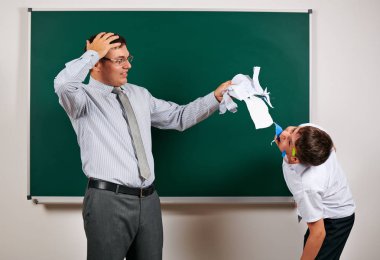 Düşük disiplinli bir öğretmen ve komik bir öğrencinin portresi. Öğrenci çok duygusal, eğlenceli ve çok mutlu, kara tahta arka planda poz - geri okul ve eğitim kavramı