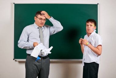 Düşük disiplinli bir öğretmen ve komik bir öğrencinin portresi. Öğrenci çok duygusal, eğlenceli ve çok mutlu, kara tahta arka planda poz - geri okul ve eğitim kavramı