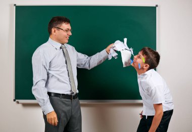 Düşük disiplinli bir öğretmen ve komik bir öğrencinin portresi. Öğrenci çok duygusal, eğlenceli ve çok mutlu, kara tahta arka planda poz - geri okul ve eğitim kavramı