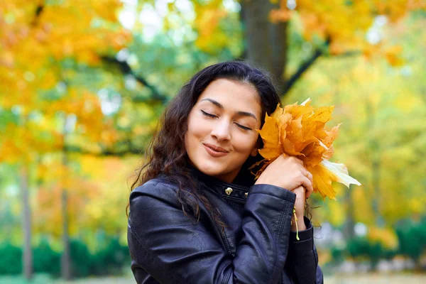 Žena s podzimním listím v městském parku, venkovní portrét — Stock fotografie