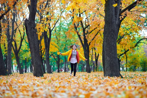 Teen dziewczyna działa z jesiennych liści w parku miejskim, portret na zewnątrz — Zdjęcie stockowe