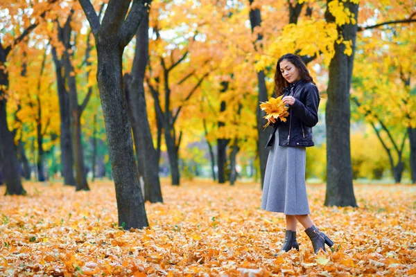 Kobieta pozowanie z jesiennych liści w parku miejskim, portret na zewnątrz — Zdjęcie stockowe