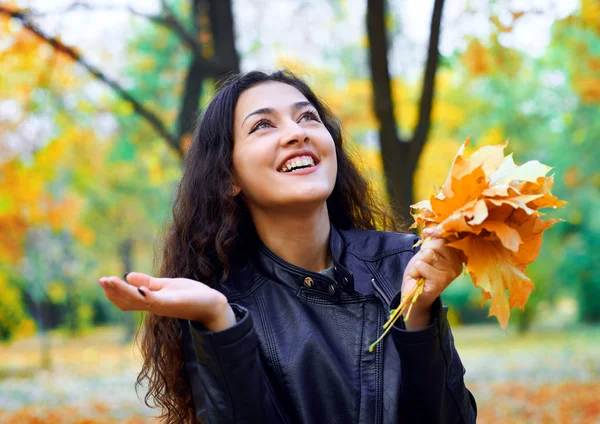 Žena s podzimním listím v městském parku, venkovní portrét — Stock fotografie