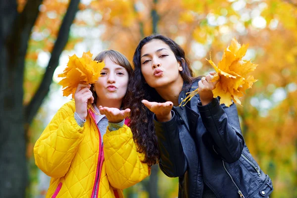 Femme faisant baiser l'air et s'amusant avec des feuilles d'automne dans le parc de la ville, portrait en plein air — Photo