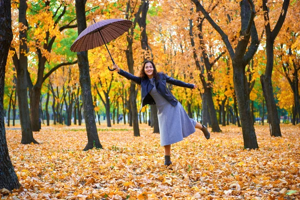 도시 공원에서 우산과 단풍을 들고 포즈를 취하는 여성, 야외 초상화 — 스톡 사진
