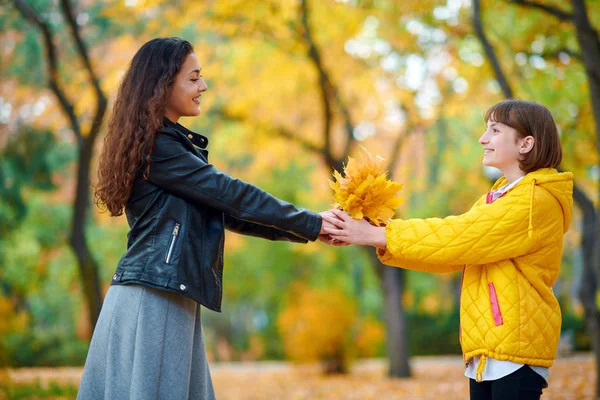 Frau posiert mit Herbstblättern im Stadtpark, Außenporträt — Stockfoto