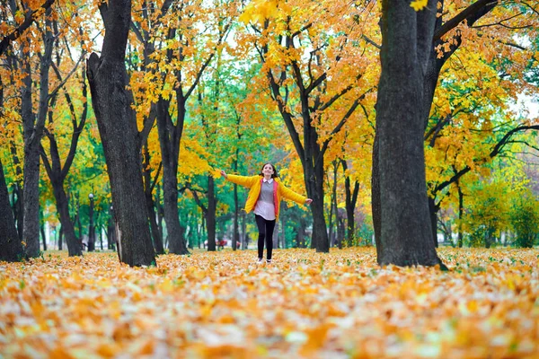 Девочка-подросток бегает с осенними листьями в городском парке, портрет на открытом воздухе — стоковое фото