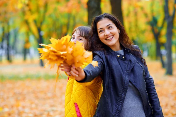 Mujer divirtiéndose con hojas de otoño en el parque de la ciudad, retrato al aire libre — Foto de Stock