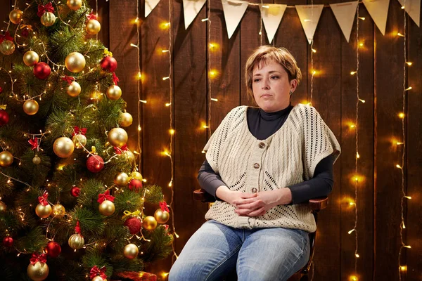 dreamy woman sitting indoor near decorated xmas tree with lights - Merry Christmas and Happy Holidays!