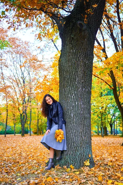 Žena s podzimním listím v městském parku, venkovní portrét — Stock fotografie