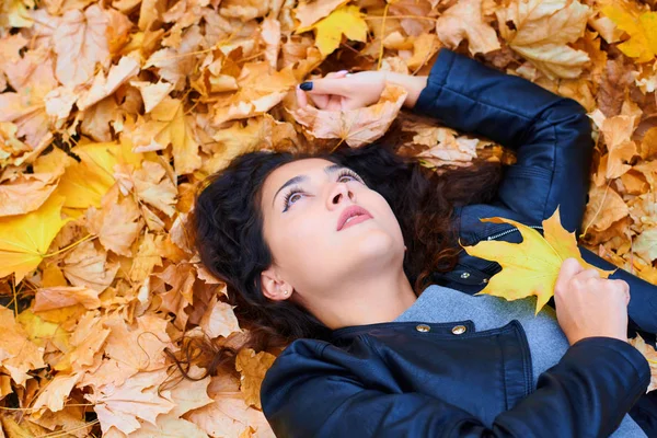 Woman lying with autumn leaves in city park, outdoor portrait — Stock Photo, Image