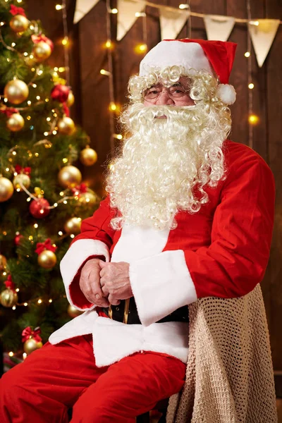 Jultomten porträtt, sitter inomhus nära dekorerad xmas träd med ljus - God Jul och Happy Holidays! — Stockfoto