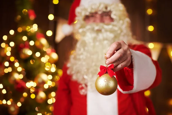 Detailní záběr Santa Claus ruce s vánoční míč dekorace, sedí uvnitř v blízkosti zdobené vánoční stromeček se světly - Veselé Vánoce a šťastné svátky! — Stock fotografie