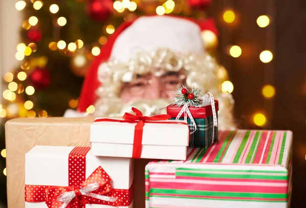 Babbo Natale in posa con molti regali, seduto vicino all'albero di Natale decorato con luci - Buon Natale e Buone Feste ! — Foto Stock