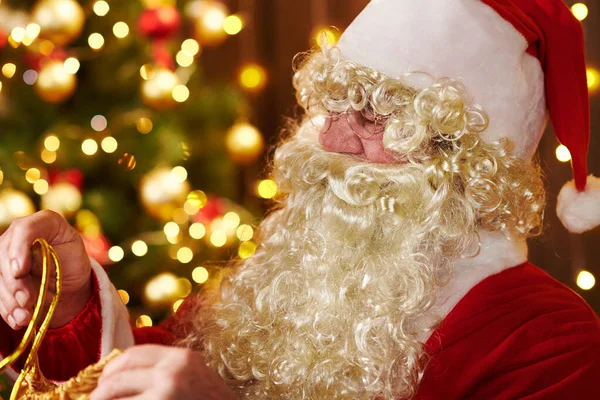 Père Noël ouvre un sac de cadeaux, assis à l'intérieur près de l'arbre de Noël décoré avec des lumières Joyeux Noël et Joyeuses Fêtes ! — Photo