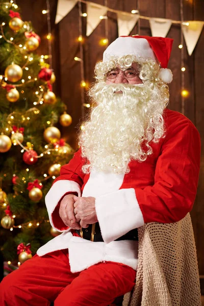 Portrait du Père Noël, assis à l'intérieur près décoré arbre de Noël avec des lumières Joyeux Noël et Joyeuses Fêtes! — Photo