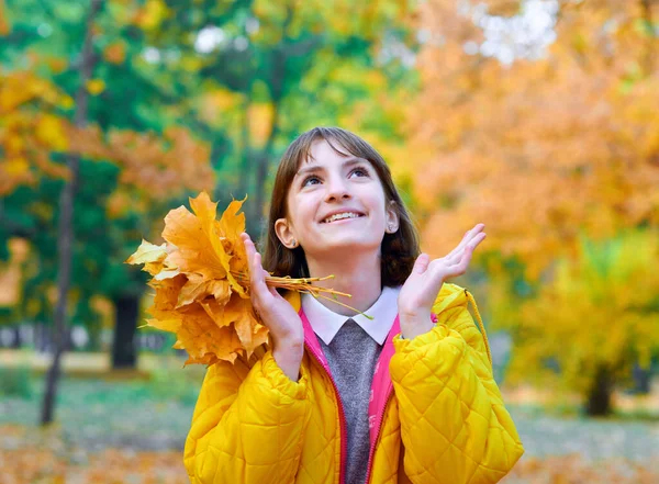 Tiener meisje poseren met herfst bladeren in stadspark, buiten portret — Stockfoto