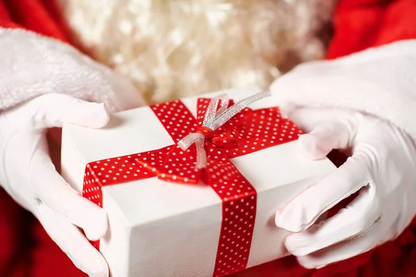 Gros plan des mains du Père Noël avec boîte cadeau, assis à l'intérieur près de l'arbre de Noël décoré avec des lumières Joyeux Noël et Joyeuses Fêtes ! — Photo