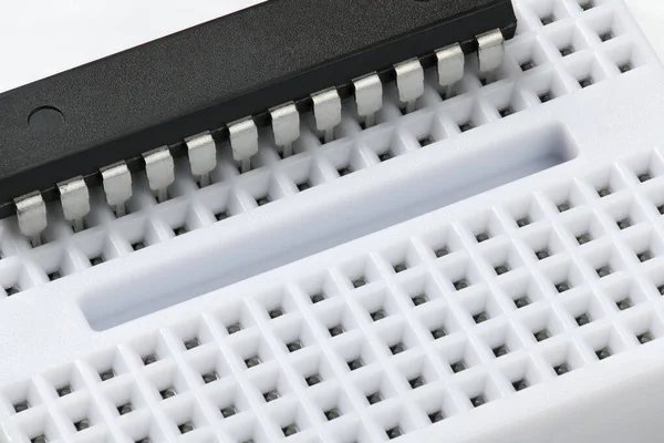 Breadboard e microchip closeup - componente eletrônico para equipamentos digitais, conceito para o desenvolvimento de circuitos de computador elétrico — Fotografia de Stock