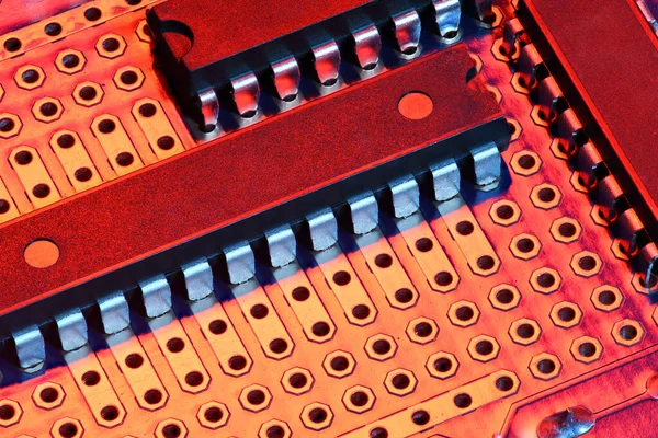 Printplaat en microchip in rood licht close-up - elektronische component voor digitale apparatuur, concept voor de ontwikkeling van elektrische computercircuits — Stockfoto