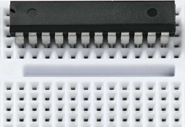 Breadboard e microchip closeup - componente eletrônico para equipamentos digitais, conceito para o desenvolvimento de circuitos de computador elétrico — Fotografia de Stock