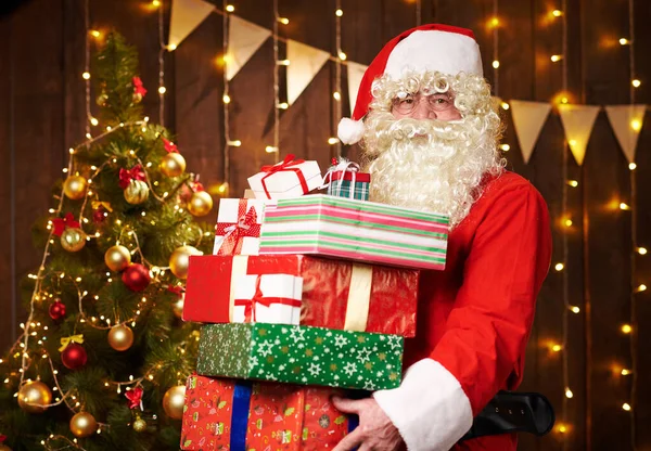 Babbo Natale in posa con molti regali, seduto vicino all'albero di Natale decorato con luci - Buon Natale e Buone Feste ! — Foto Stock