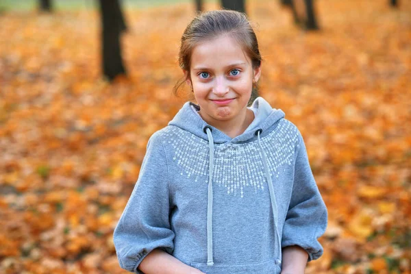 Retrato de menina no parque da cidade de outono, posando, sorrindo e se divertindo. Árvores e folhas amarelas brilhantes — Fotografia de Stock