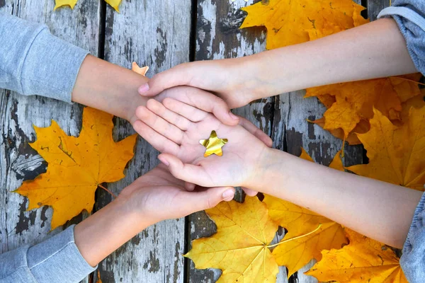 Руки з осіннім листям над дерев'яним тлом — стокове фото